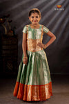 Woman wearing a traditional outfit with green and orange colors against a dark background