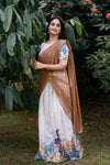 Woman in a traditional saree with a floral blouse against a green leafy background