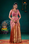 Woman in a pink and gold saree standing against a dark green background with decorative elements.