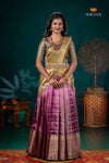 Woman wearing a traditional saree with a green and purple pattern in a decorated room.