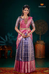 Woman in a traditional pink and purple saree with a dark background