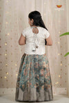 Woman wearing a white blouse with cut-out back and a floral skirt against a curtain background
